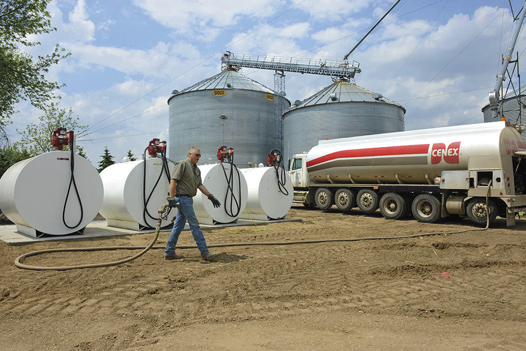Man walking hose from Cenex propane truck to propane tanks