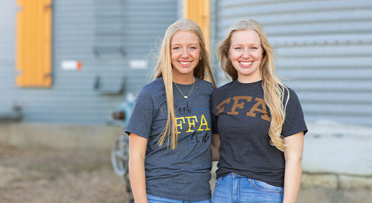 Two young women standing in front of a grain bin