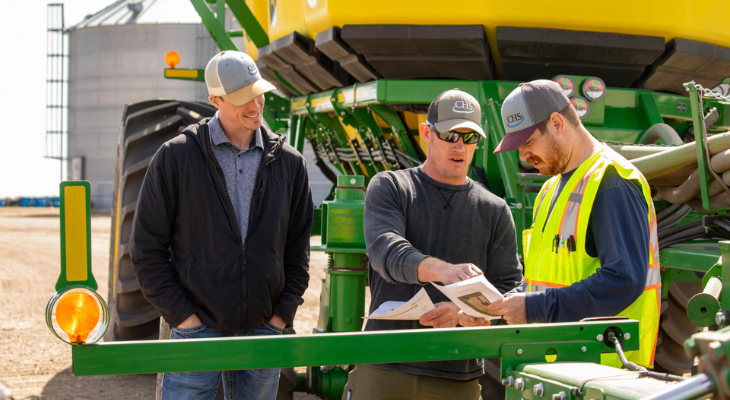 Three men standing in front of farm equipment